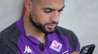 Sofyan Amrabat of Fiorentina checks his phone during a pre-season friendly against Grosseto in August 2023.