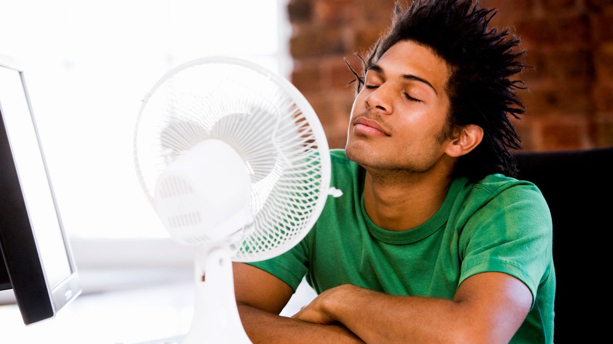 Man sat in front of desk fan