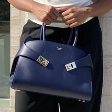 A woman holding a midnight blue handbag from Ferragamo