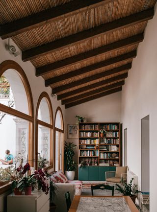 Wooden bookcase in library sunroom with beams, upholstered furniture and a marble tabletop