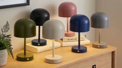 a group of Dunelm wireless rechargable lamps in various colours on a sideboard