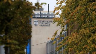 A building with the Northumbria University logo displayed, partially obscured by trees