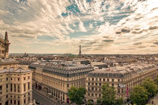 A photograph of Paris with the Eiffel Tower in the background and the city's streets in the foreground.
