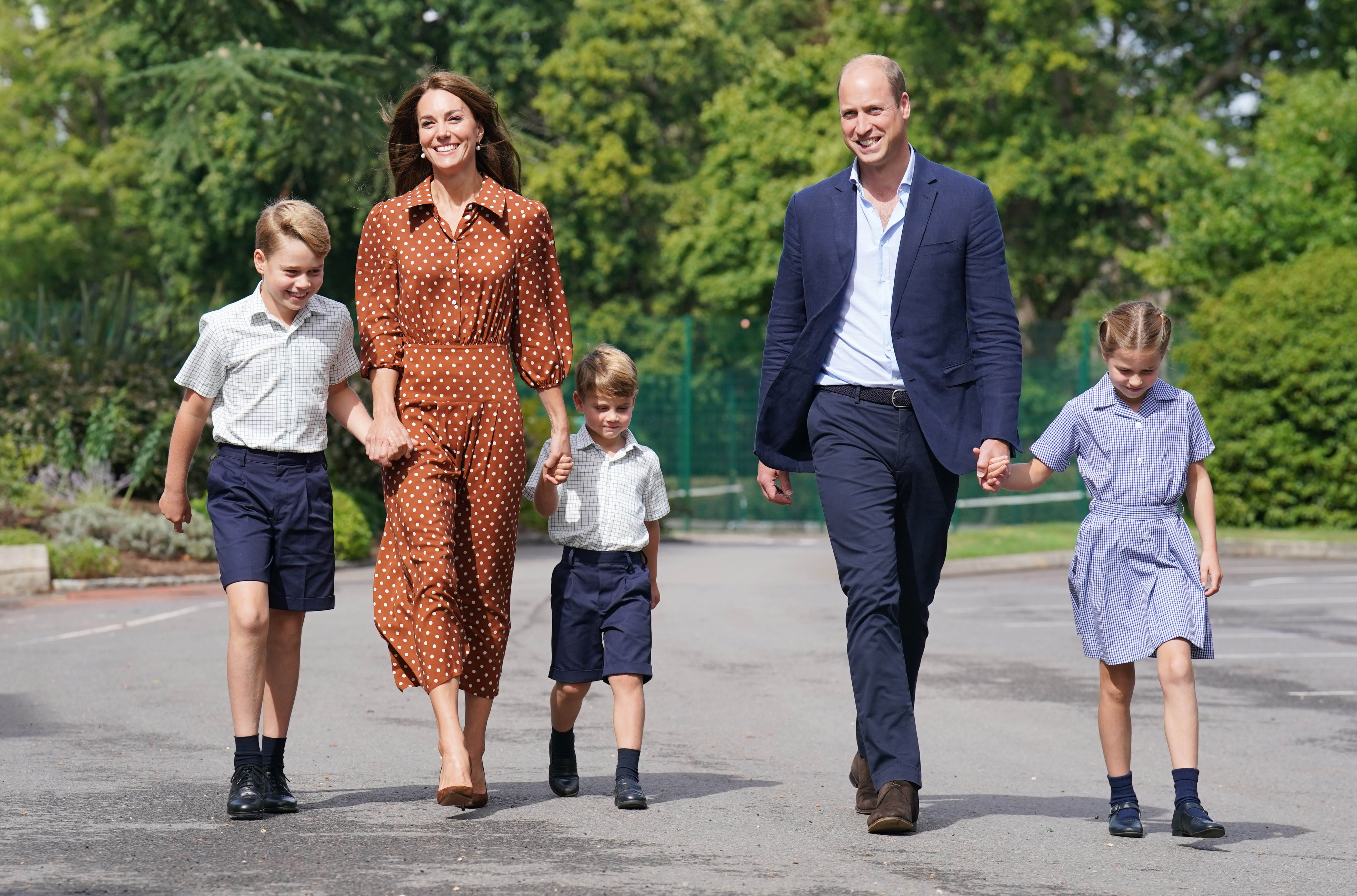 Prince George, Prince Louis and Princess Charlotte holding hands with Princess Kate and Prince William walking to their first day of school
