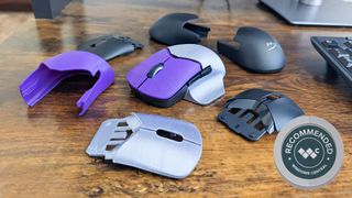 HyperX Pulsefire Saga Pro Wireless gaming mouse with 3D printed purple clicker buttons and a 3D printed silver back shell with a thumb rest. It's surrounded by 3D printed shells and swappable shells. 