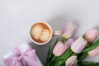 A coffee with a pair of light pink tulips.