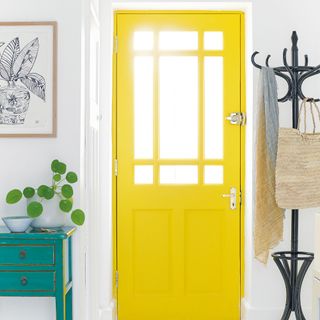 a bright yellow front door as seen from a white hallway
