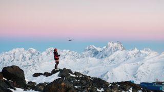 ountaineer flies drone towards mountain summit