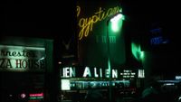 a movie theatre marquee above a busy city street at night with the words "alien: in space no one can hear you scream"