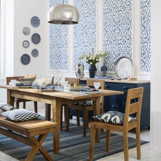 White dining room with panels of blue patterned wallpaper and wooden furniture
