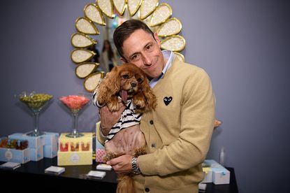 Jonathan Adler holding a dog at an event and smiling.