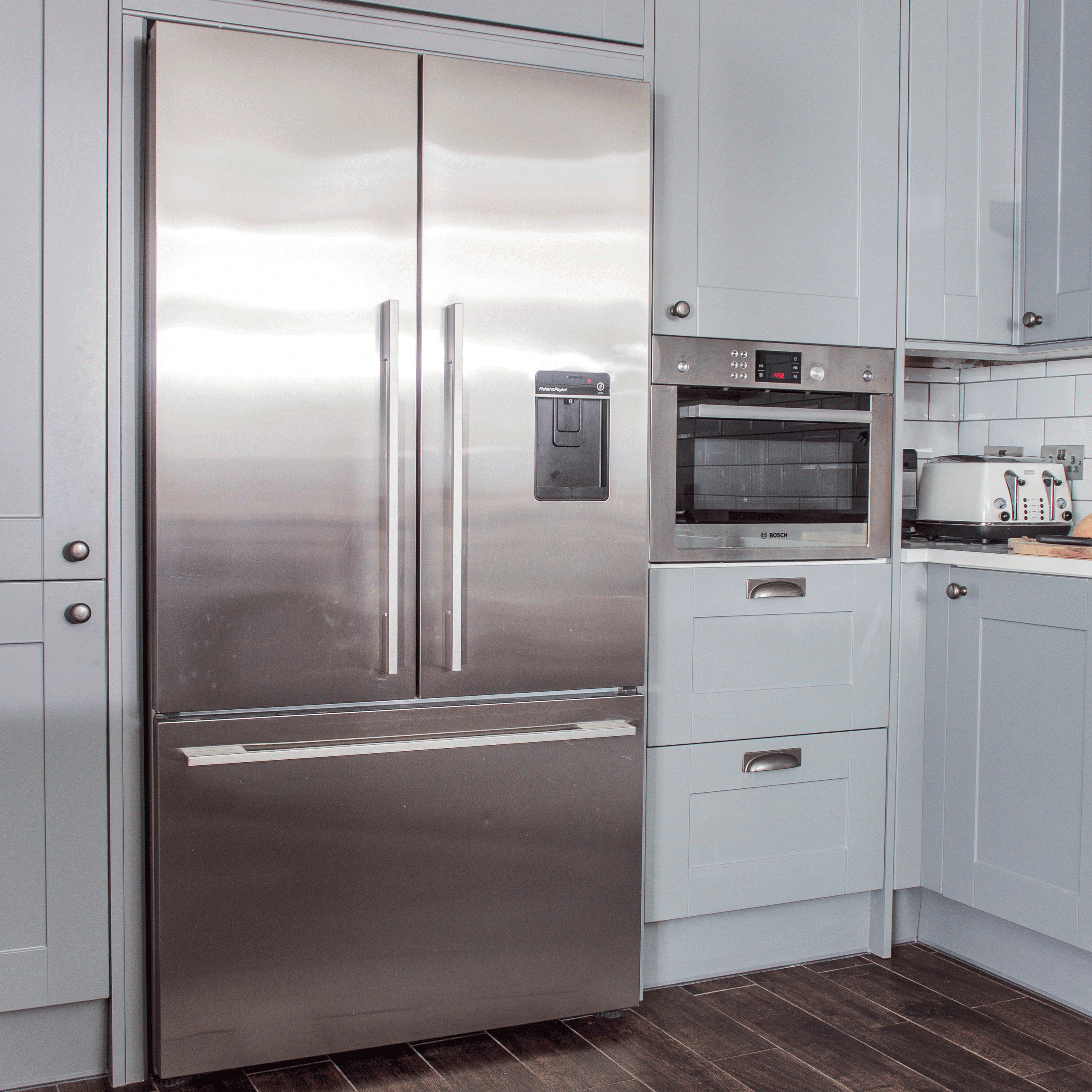 kitchen with white cabinets silver refrigerator and wooden flooring