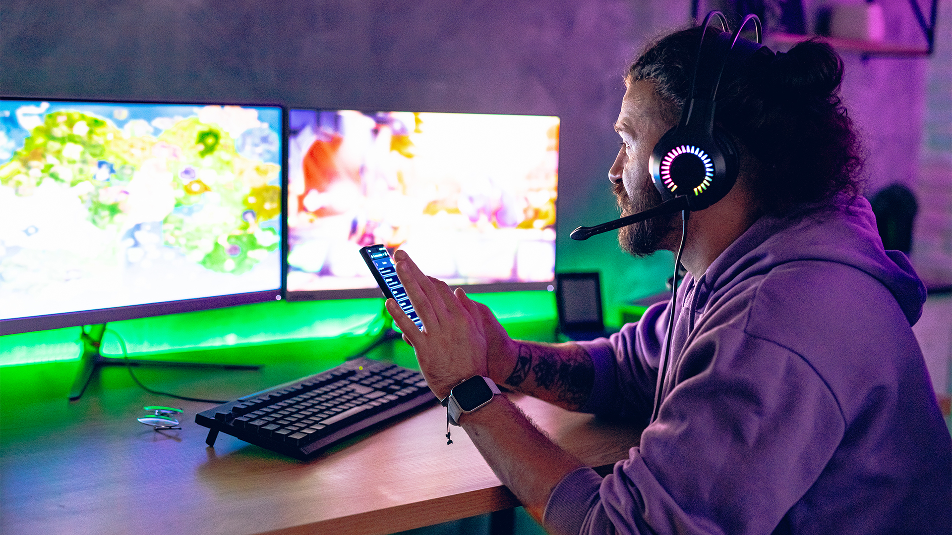 Man using mobile phone while playing games in room with neon lighting