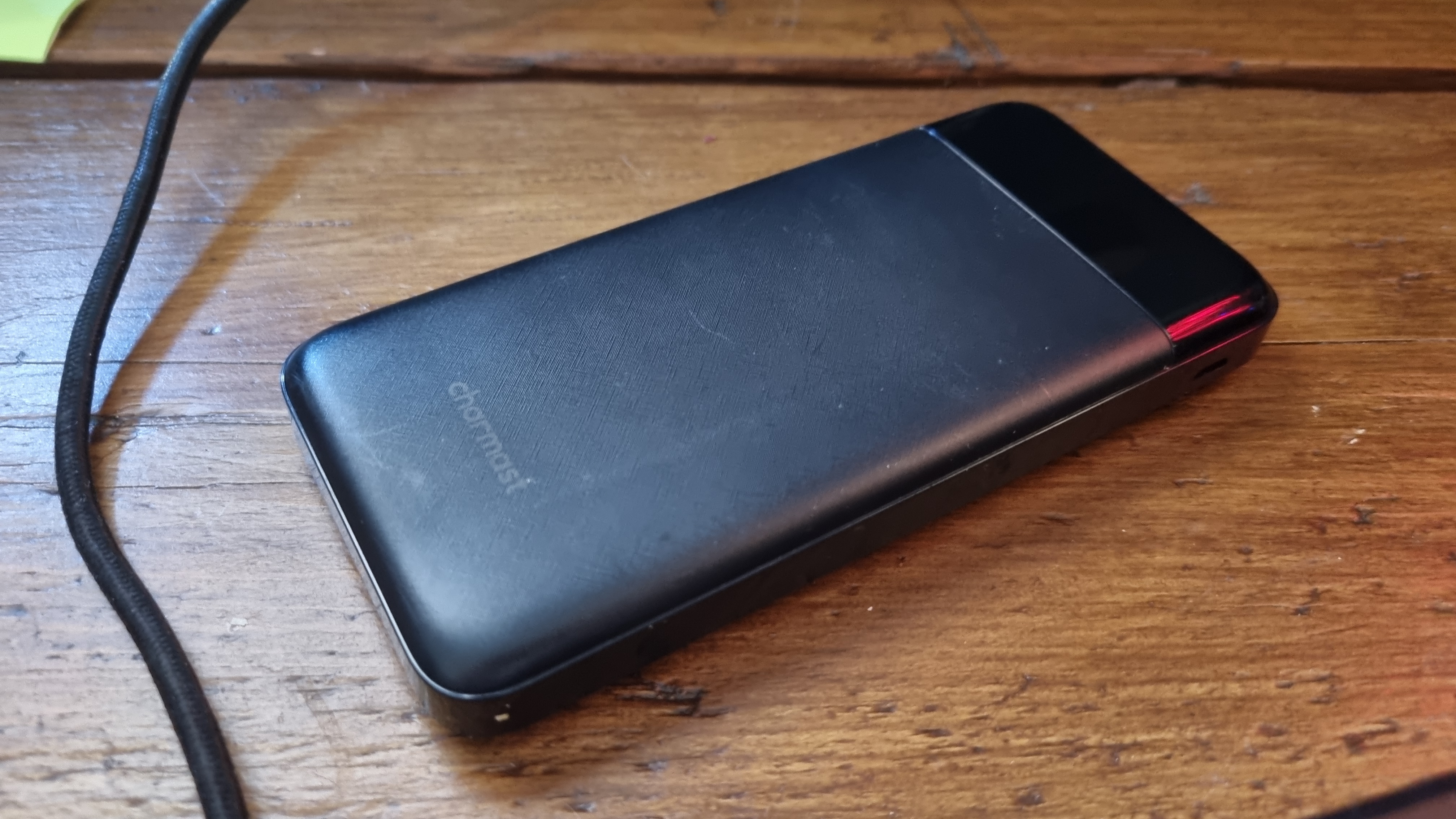 A Charmast portable power bank on a wooden desk