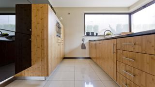A contemporary narrow kitchen with wood finish fittings and integrated appliances
