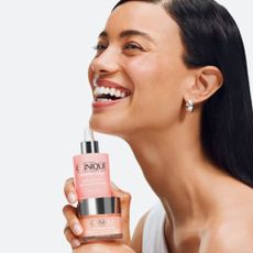 Woman smiling while holding Clinique Moisture Surge moisturisers 