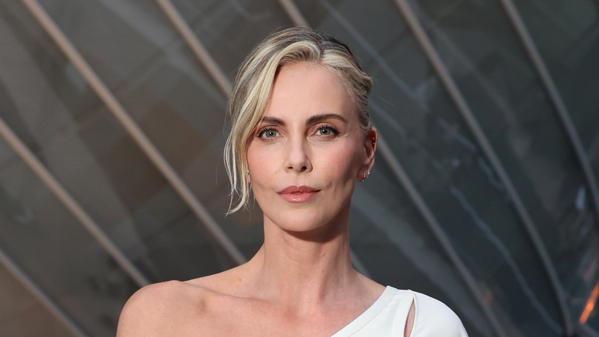 Charlize Theron in a white off-the-shoulder dress with minimal makeup and an updo.