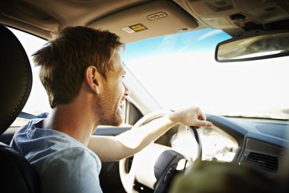 Smiling man driving car on a sunny day