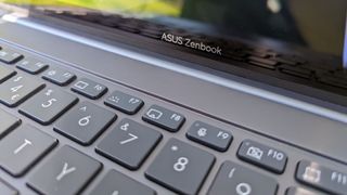 An ASUS Zenbook 14X OLED laptop sitting in a nature scene