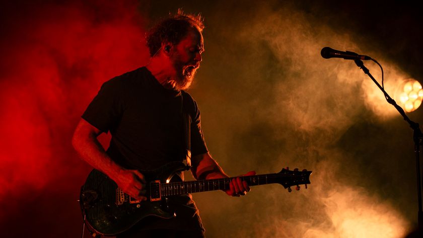 Karnivool guitarist Mark Hosking plays his PRS guitar onstage amid dry ice and red and yellow stage lights