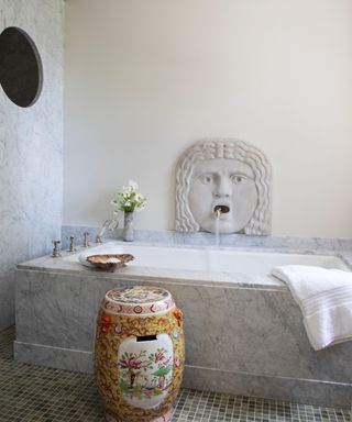 bathroom with lion's head fountain over the bath and porthole in shower wall