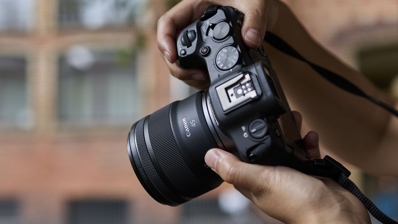 Canon RF 45mm F1.2 STM lens in the hand, attached to a Canon camera