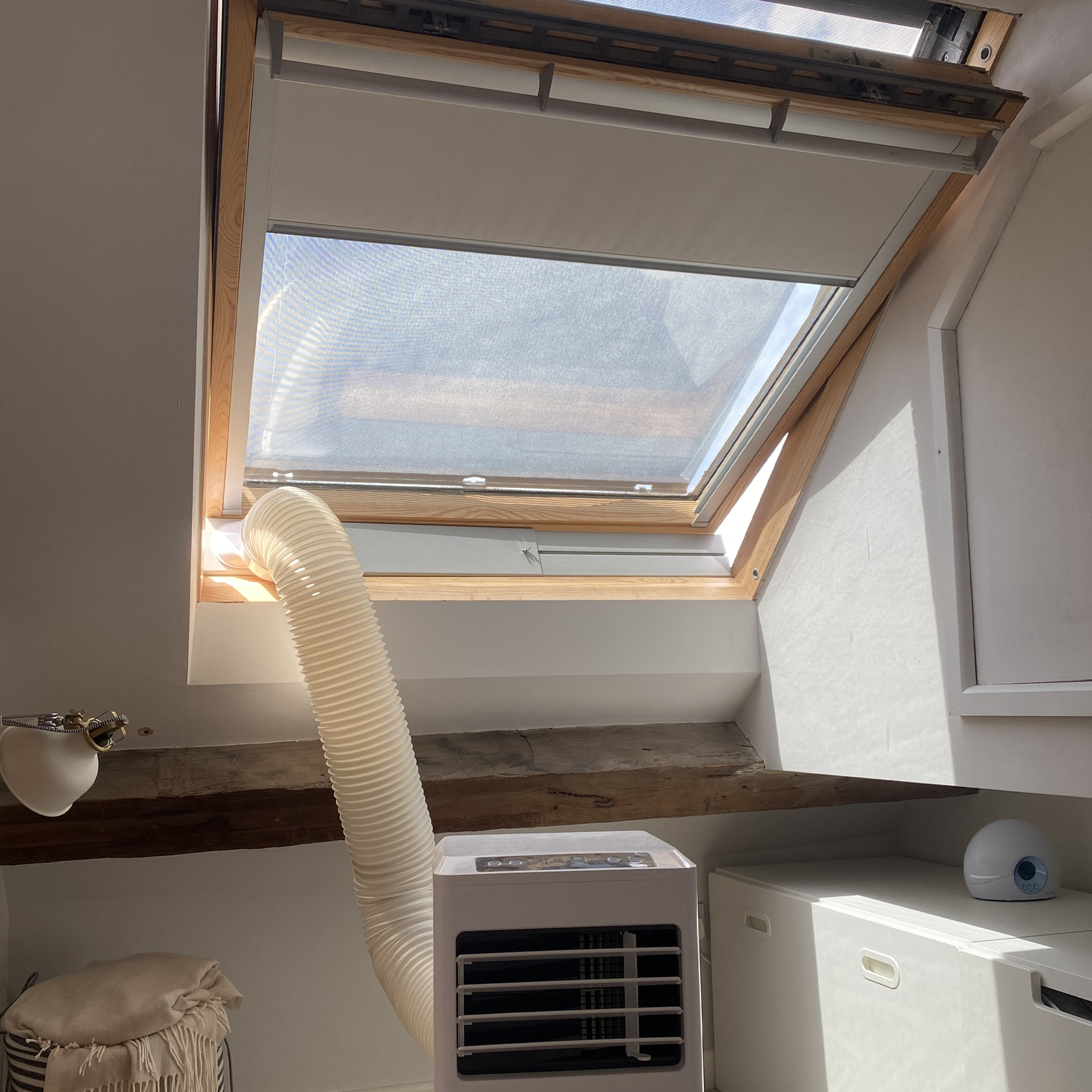 A portable air conditioner being vented out of a loft window