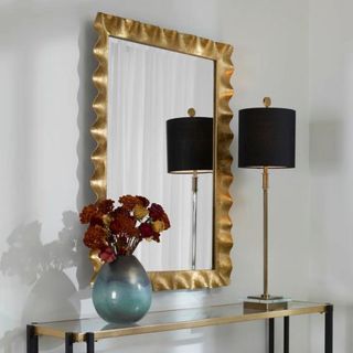 A gold, textured mirror over a console table from Wayfair