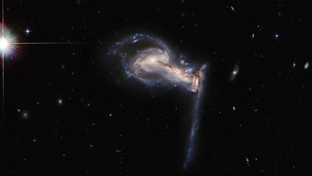 The three galaxies are yanking strands of material from each other as they spiral ever closer.