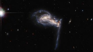 The three galaxies are yanking strands of material from each other as they spiral ever closer.