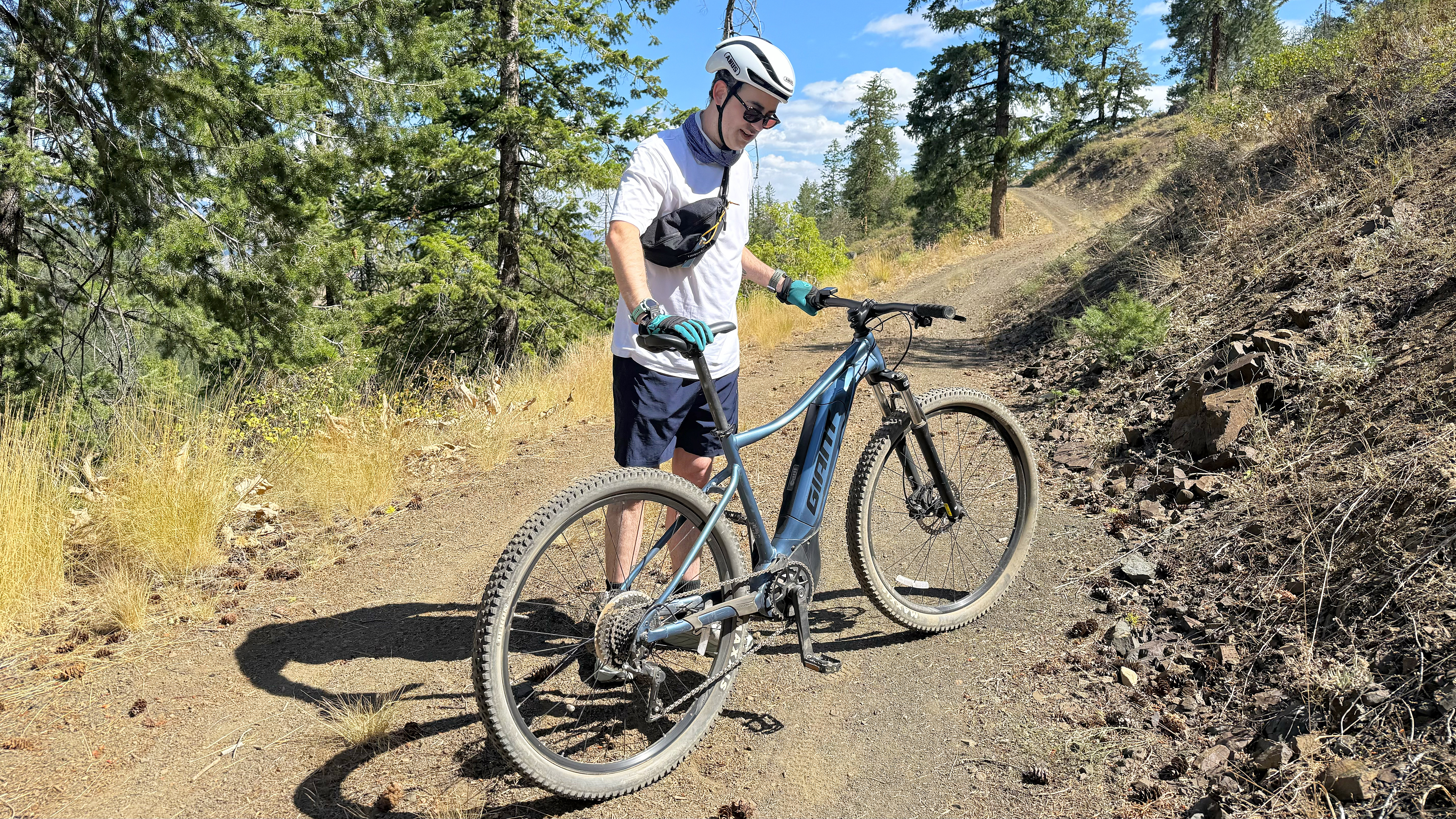 Senior writer Dan Bracaglia adjusting his e-mountain bike on the side of a trail