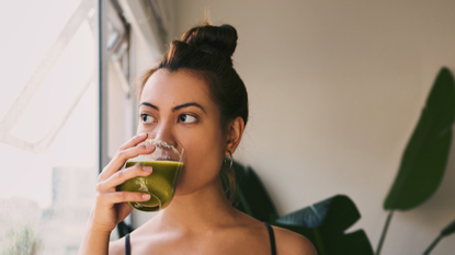 Fitness woman drinking a healthy green smoothie juice for a detox weight  loss cleanse. Happy sporty