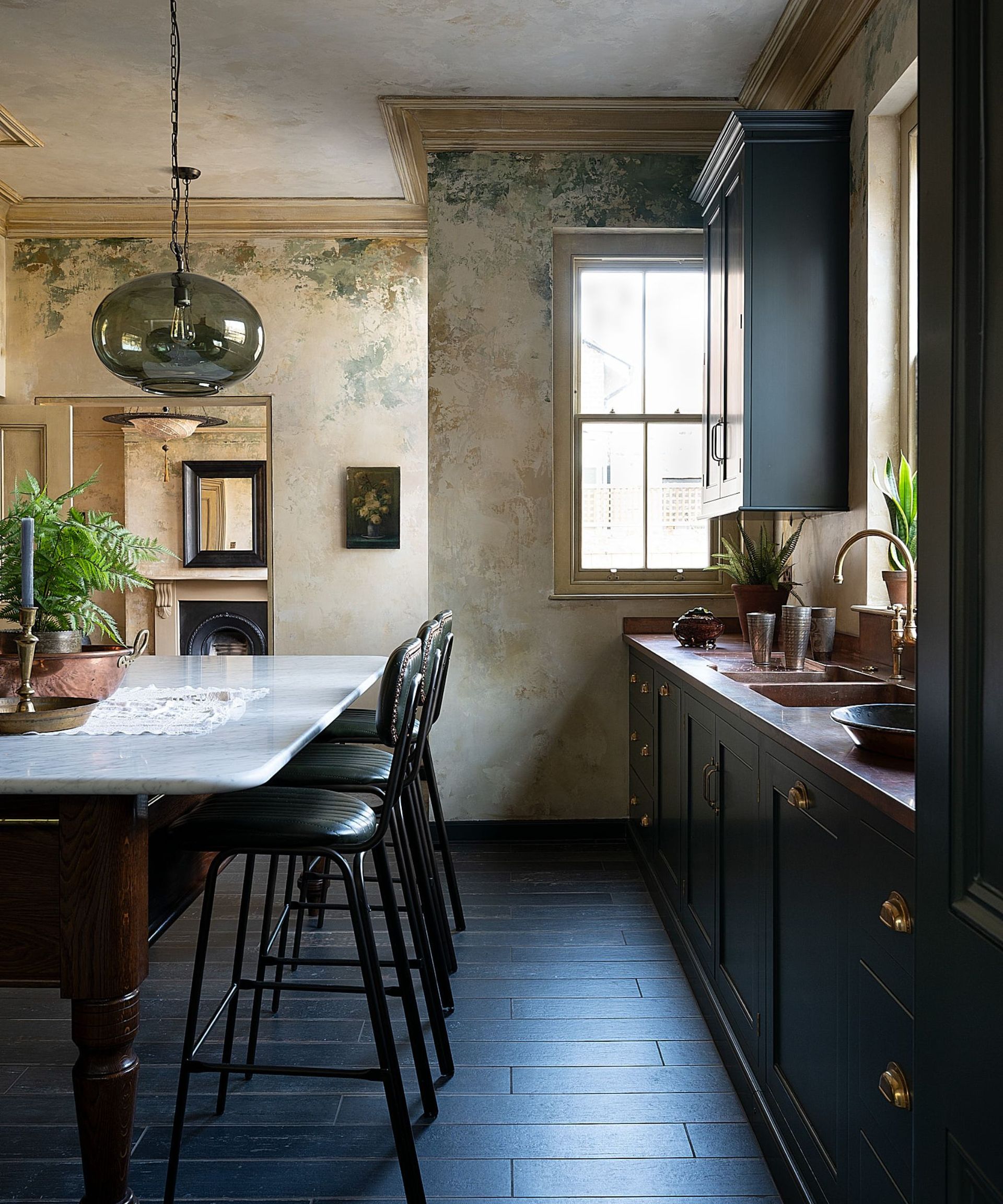 A dark green kitchen with copper countertops and a wooden freestanding island