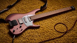 Ibanez Q54W: the headless electric guitar is finished in Copper Metallic Matte and photographed against a thick light-tan colored carpet.
