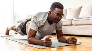 Man in workout clothes on an exercise mat working on how to do a plank