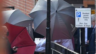 Paramedics use umbrellas to shield individual where Prince Phillip had been staying