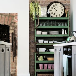 Green vintage shelving with exposed brick wall in kitchen