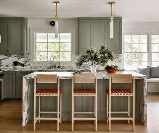 A green and marble kitchen with a large bouquet of spring flowers displayed in a vase of the island