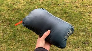 Hand holding the Helly Hansen Verglas 2.0 down jacket packed into its own pocket