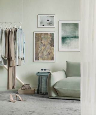 A green walk in wardrobe with clothes rail and slubby green velvet sofa