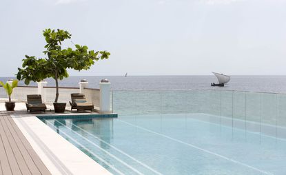 Park Hyatt infinity pool, with sun loungers under tree, overlooking Indian Ocean