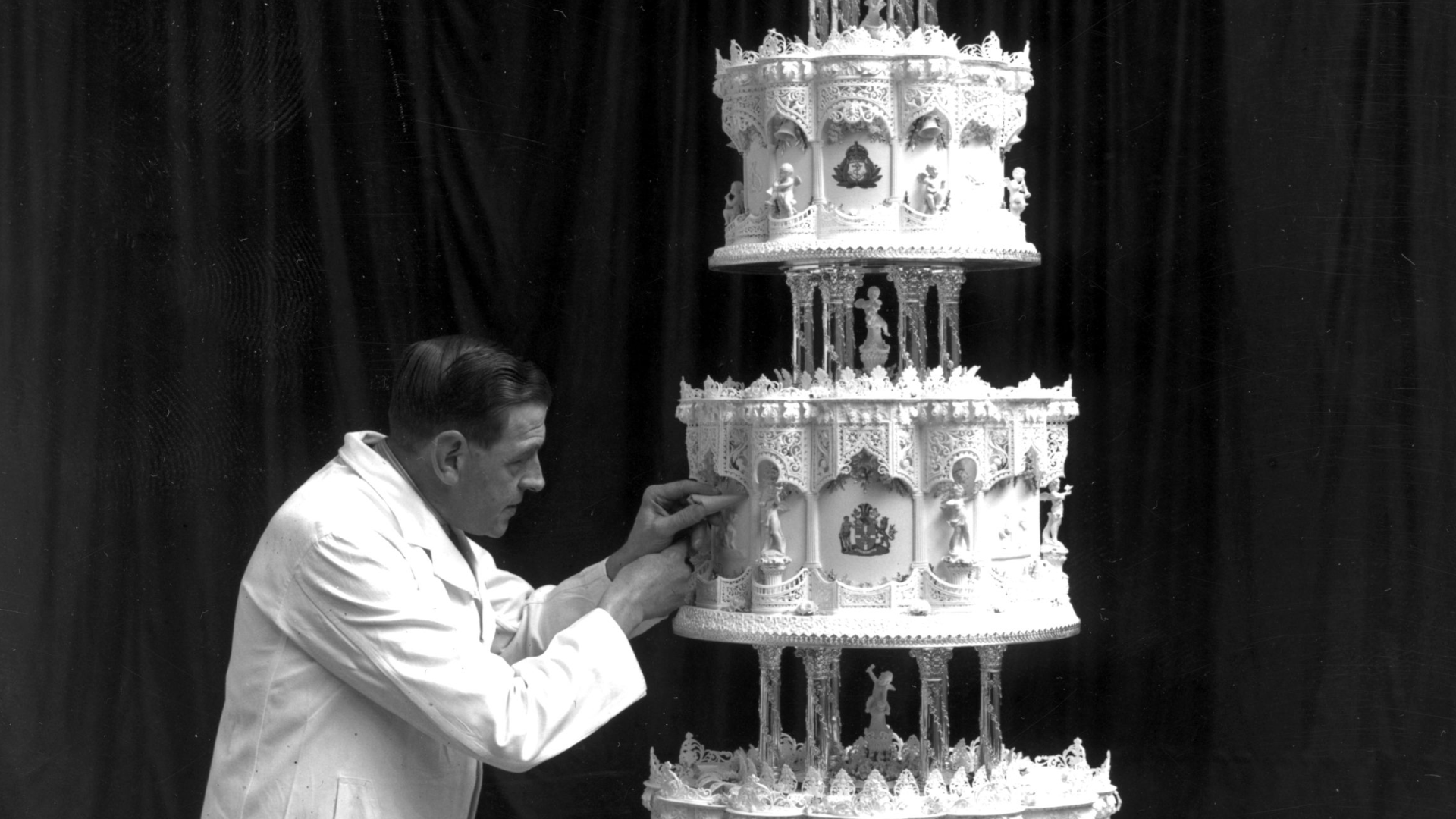 A man putting detail on Queen Elizabeth's wedding cake