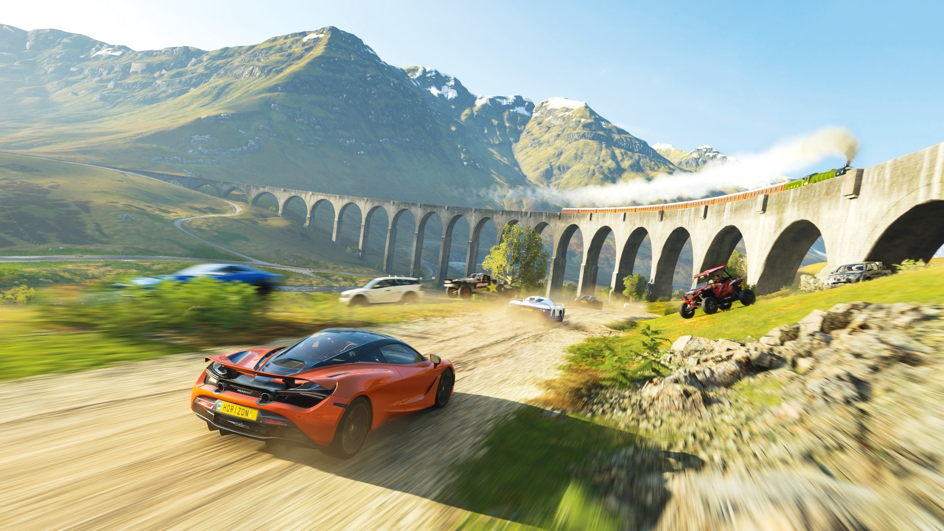 Cars race through Scottish countryside in Forza Horizon 4, alongside a bridge with a steam train on it
