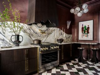 a burgundy red kitchen with a marble backsplash