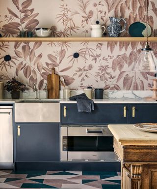 An example of small kitchen storage ideas showing a kitchen with dark blue and metallic cabinets and drawers in front of a pink and red floral wall