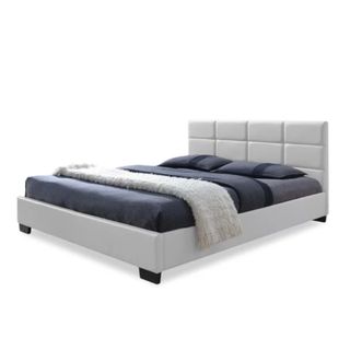 A white upholstered bed with blue bedding