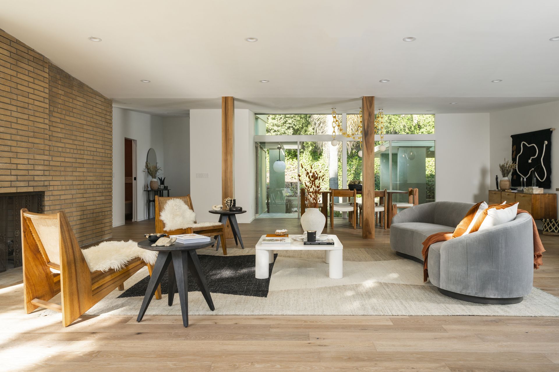 A boho style living room with a curved sofa, wooden chairs and shag throws