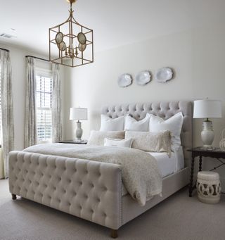 Basement bedroom with neutral carpet and walls, upholstered bed, and pendant light