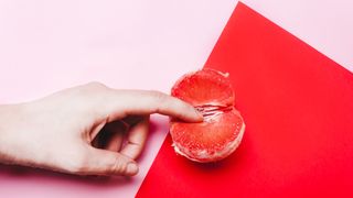 person touching grapefruit on pink and red background