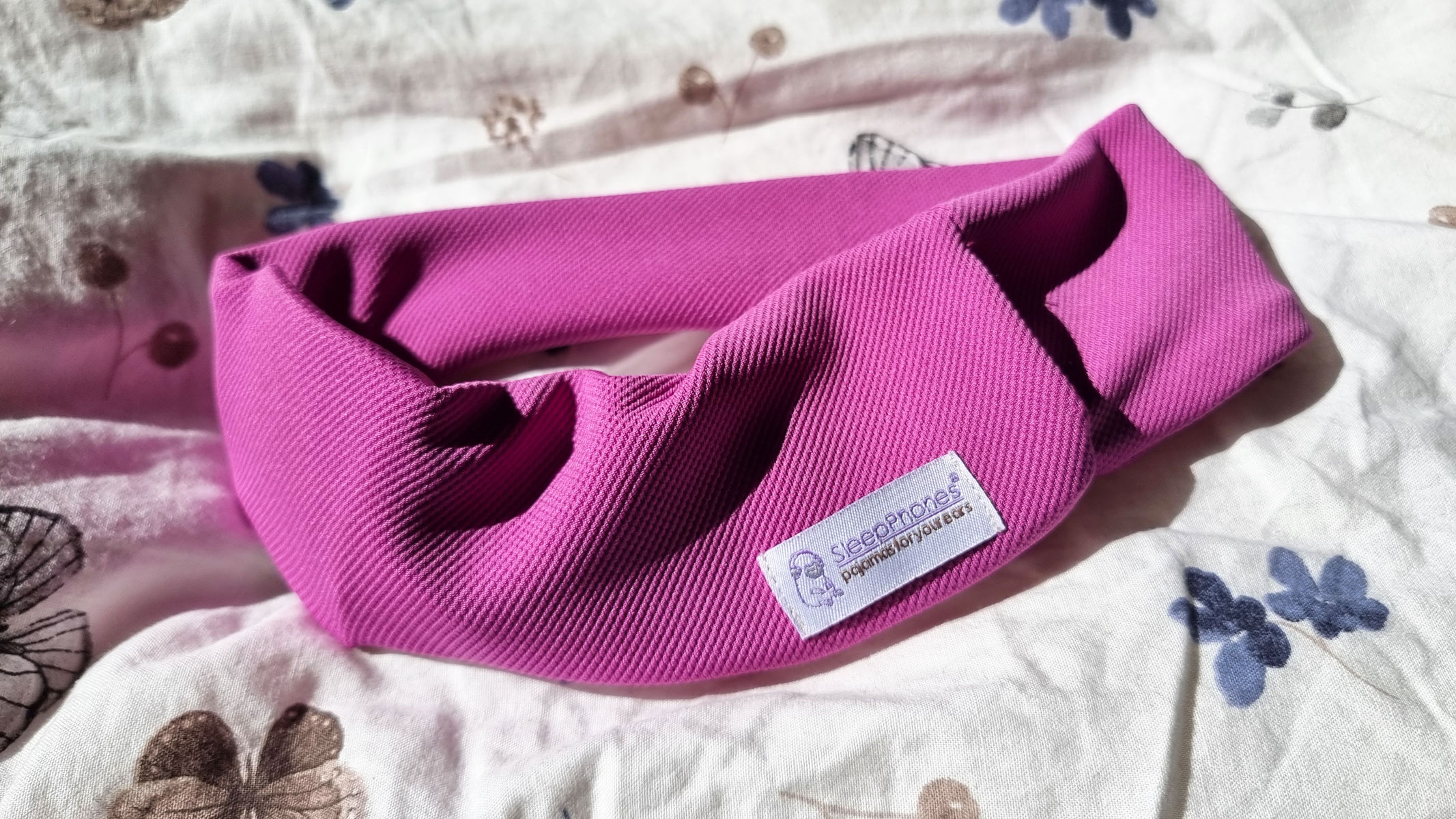 Pink AcousticSheep SleepPhones V8 on a white pillow